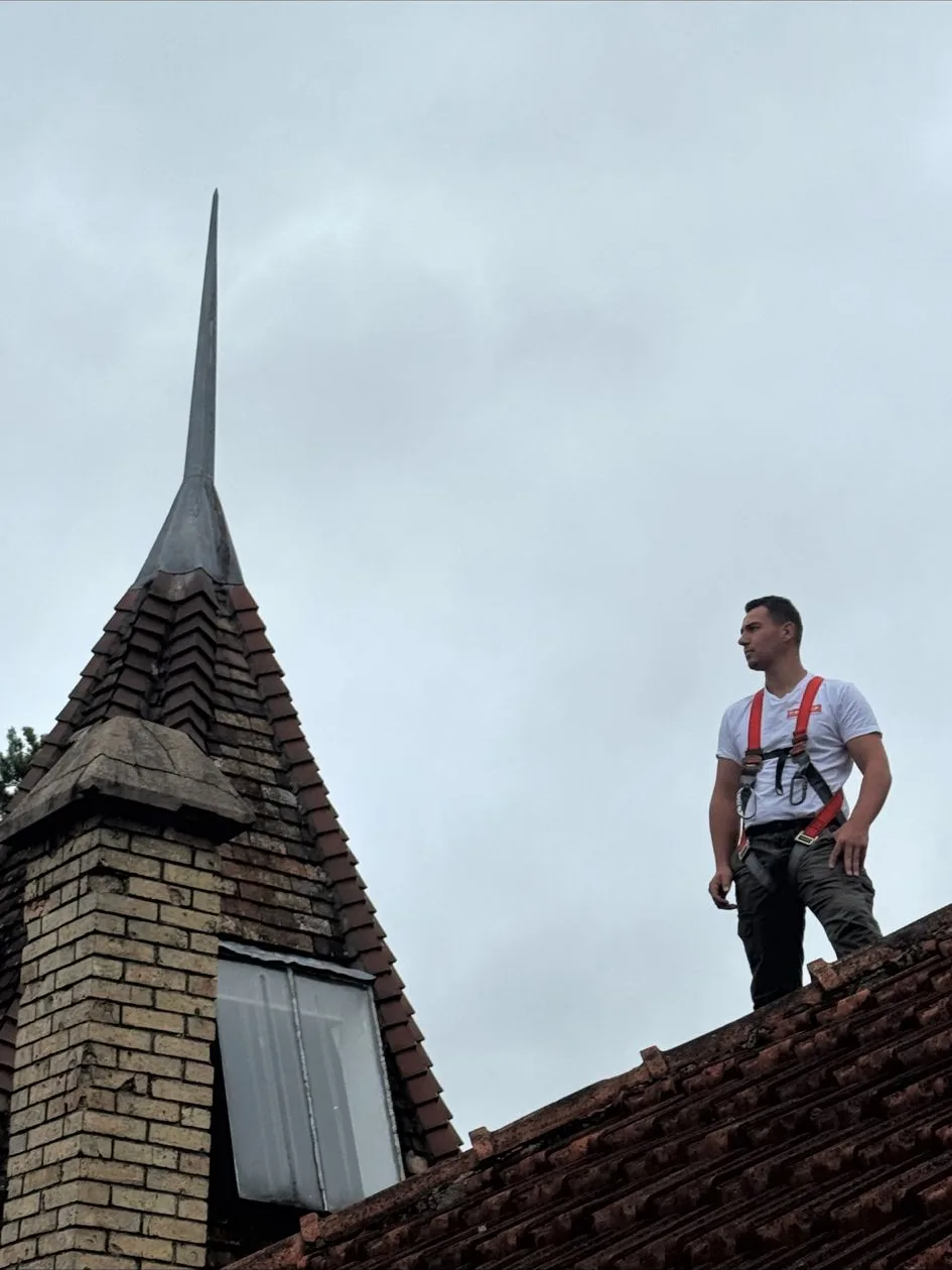 Artisan Yvelines Rénovation sur une toiture en tuiles près d'un clocheton